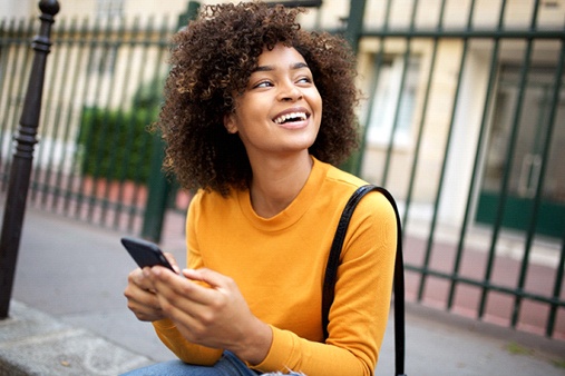 person smiling and sitting on a city curb