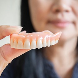 A closeup of a removable denture held by a hand