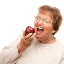 Older woman with dentures biting an apple