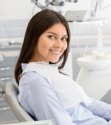 Female dental patient sitting and smiling in dental chair