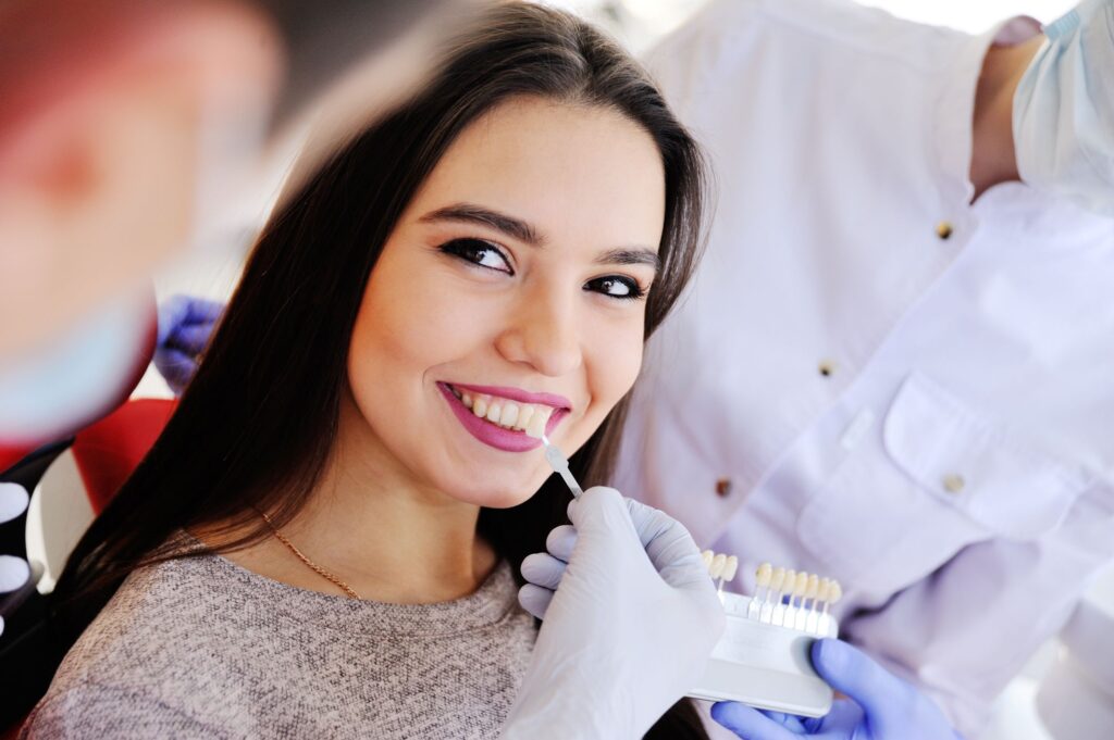 Woman smiling as dentist holds shade guide to her teeth