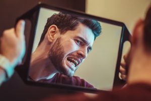 man looking curiously in mirror  