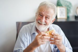 Man with dental implants eating burger